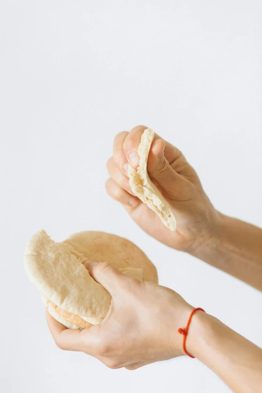 a person holding a piece of bread in their hands, by Nina Hamnett, soft volume absorbation, serving burgers, brood spreading, koji morimoto