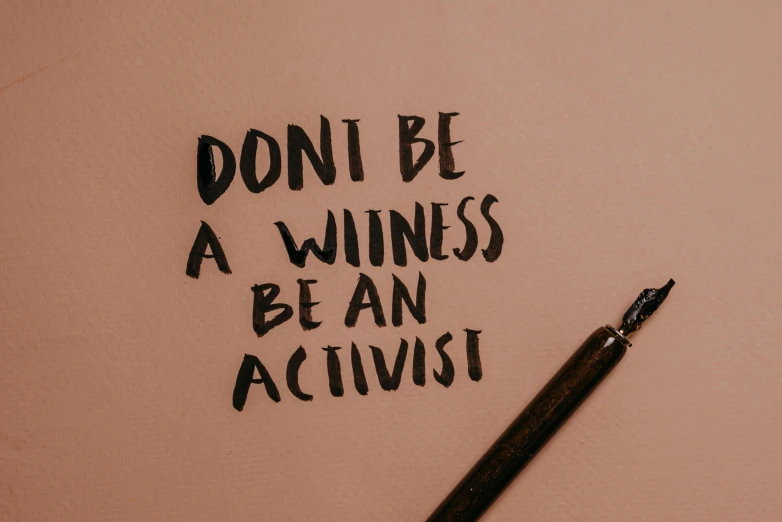 a pen sitting on top of a piece of paper, by Liza Donnelly, unsplash contest winner, feminist art, protest, the witness, lettering, wearing a brown