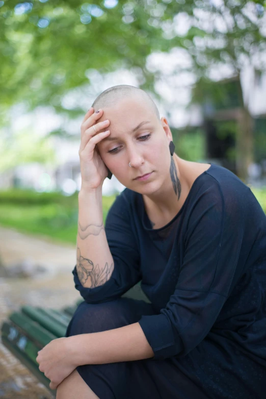 a woman sitting on a bench with her head in her hands, bald patch, tumours, beth cavener, square