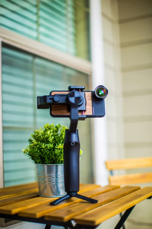 a camera sitting on top of a wooden table, mobile gimball camera, moment cinebloom filter, detailed product image, monocular