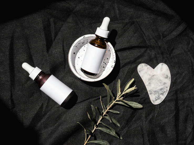 a couple of bottles sitting on top of a table, by Julia Pishtar, trending on pexels, skincare, floating symbols and crystals, black oil, herbs