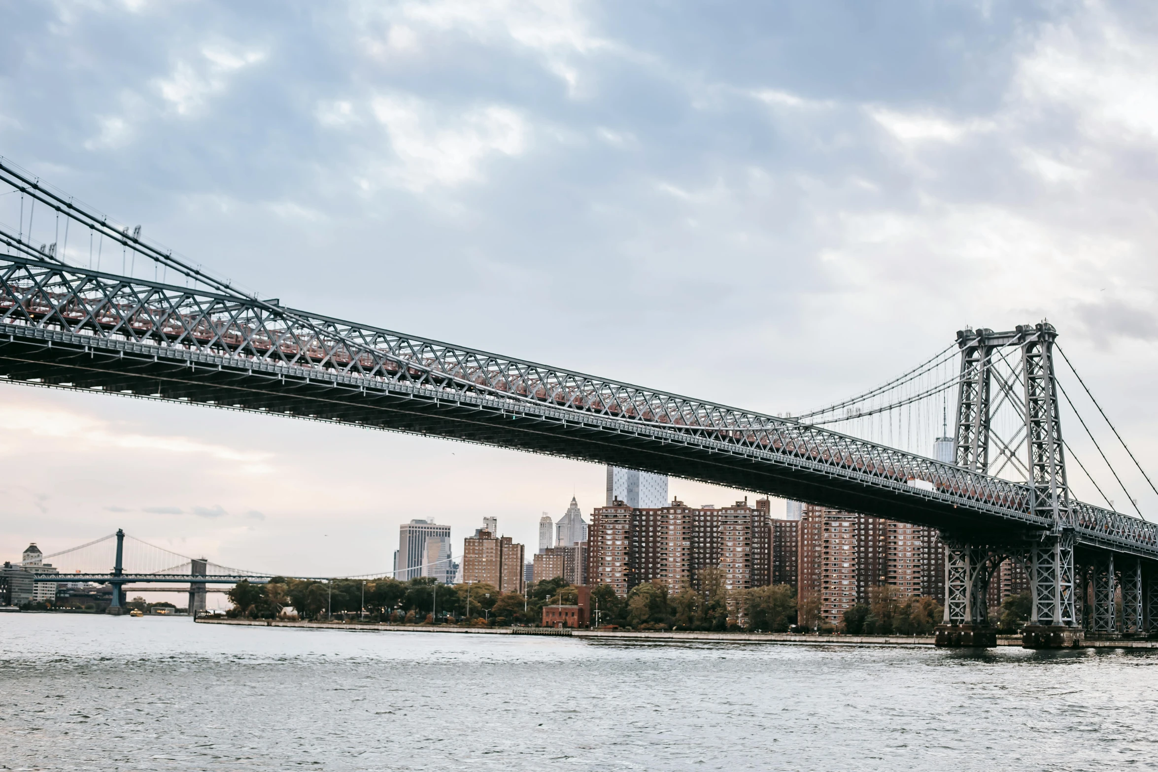 a bridge over a body of water with a city in the background, inspired by Thomas Struth, unsplash contest winner, brooklyn, ignant, metallic bridge, low angle wide shot