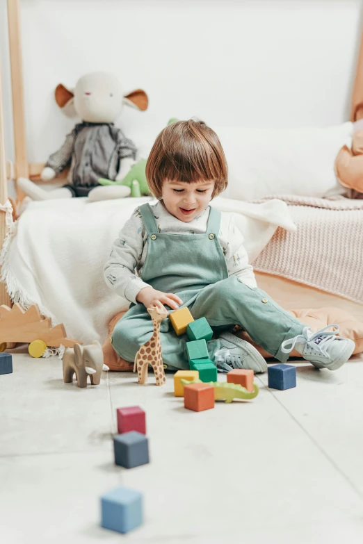 a small child sitting on the floor playing with blocks, pexels contest winner, all overly excited, inside a child's bedroom, scientific, grey