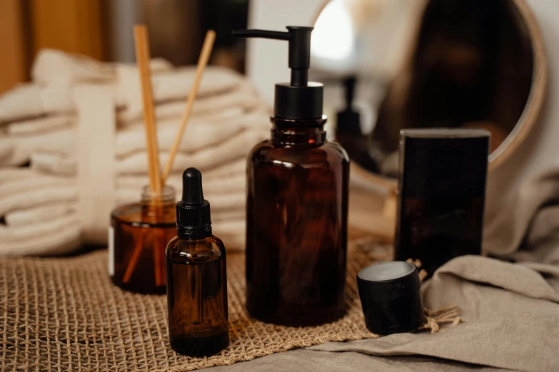 a couple of bottles sitting on top of a table, a still life, trending on pexels, skincare, brown robes, black, homemade