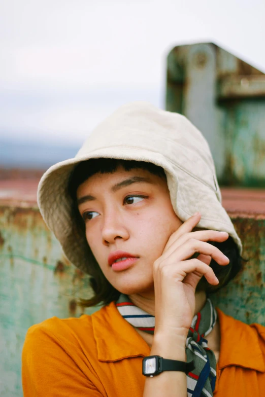 a woman wearing a hat talking on a cell phone, by Miyamoto, unsplash, realism, kiko mizuhara, bucket hat, beige, wavy