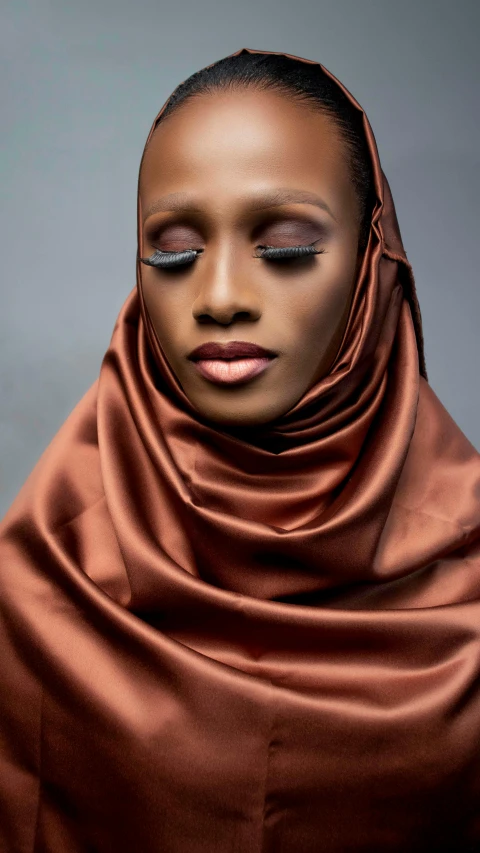 a woman wearing a brown scarf over her head, an album cover, inspired by Nyuju Stumpy Brown, trending on pexels, hurufiyya, glossy skin, fashion shoot 8k, brown:-2, somali woman