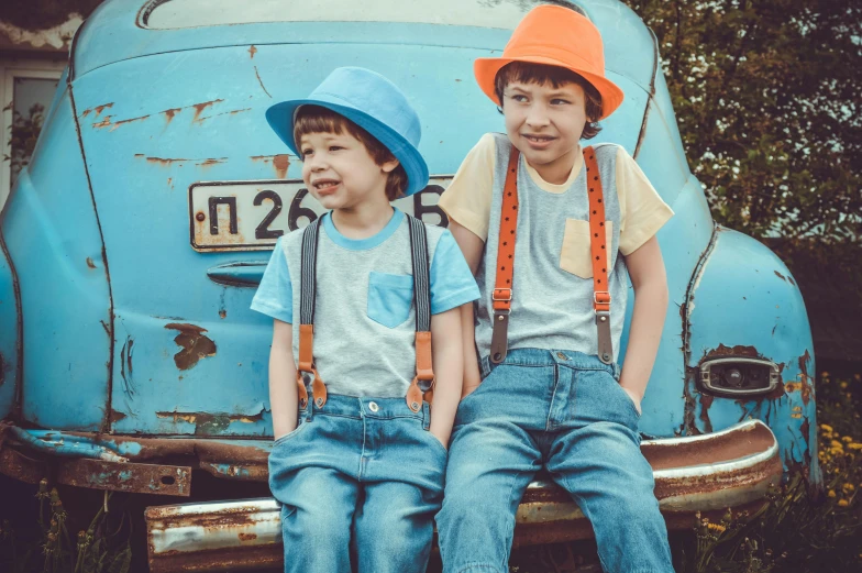 two young boys sitting on the back of a blue car, by Joe Bowler, pexels, wearing a straw hat and overalls, teal and orange colours, vintage theme, avatar image