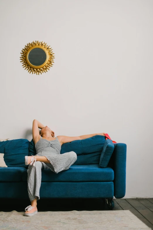 a woman laying on top of a blue couch, by Rachel Reckitt, pexels contest winner, minimalism, sunburst behind woman, yawning, sitting in a waiting room, profile image