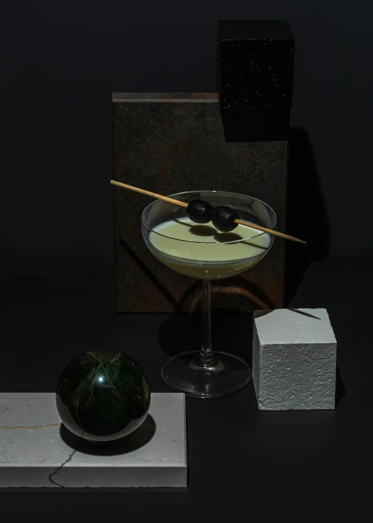 a glass filled with liquid sitting on top of a table, a still life, inspired by Carlo Martini, suprematism, flying black marble balls, avacado dream, angelina stroganova, small square glasses