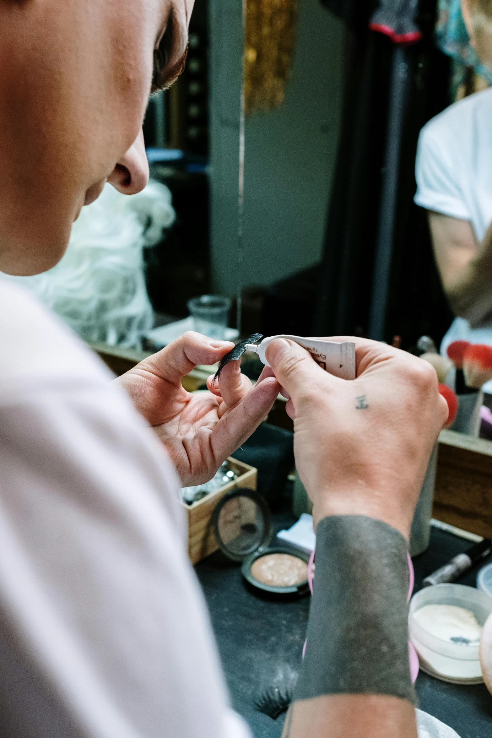 a man getting his nails done in front of a mirror, a tattoo, by Nina Hamnett, trending on unsplash, heavy makeup, white powder makeup, production photo, theater dressing room