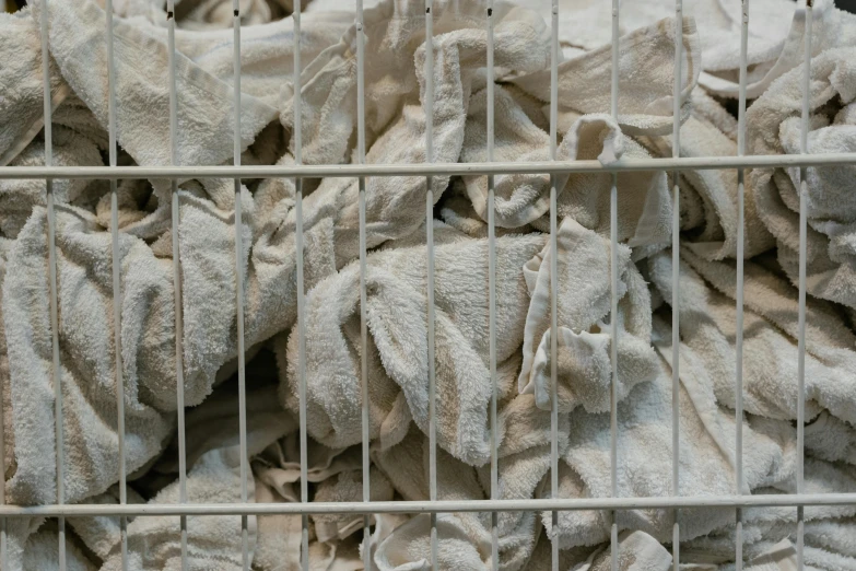 a pile of towels sitting inside of a metal cage, inspired by Sarah Lucas, unsplash, arte povera, white clay, detail shot, crowds, 2010s