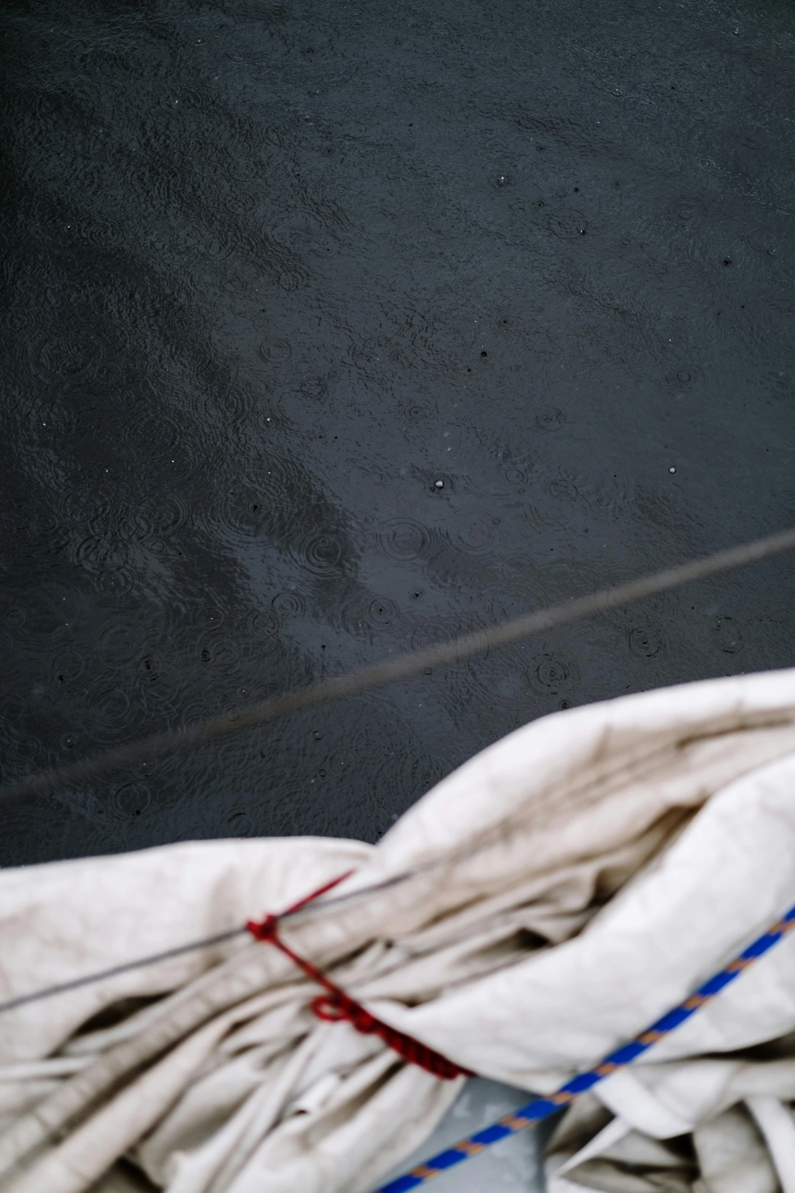 a pair of scissors sitting on top of a pile of cloth, an album cover, by Elsa Bleda, unsplash, lyrical abstraction, wet asphalt, on a boat, rainy wet, black