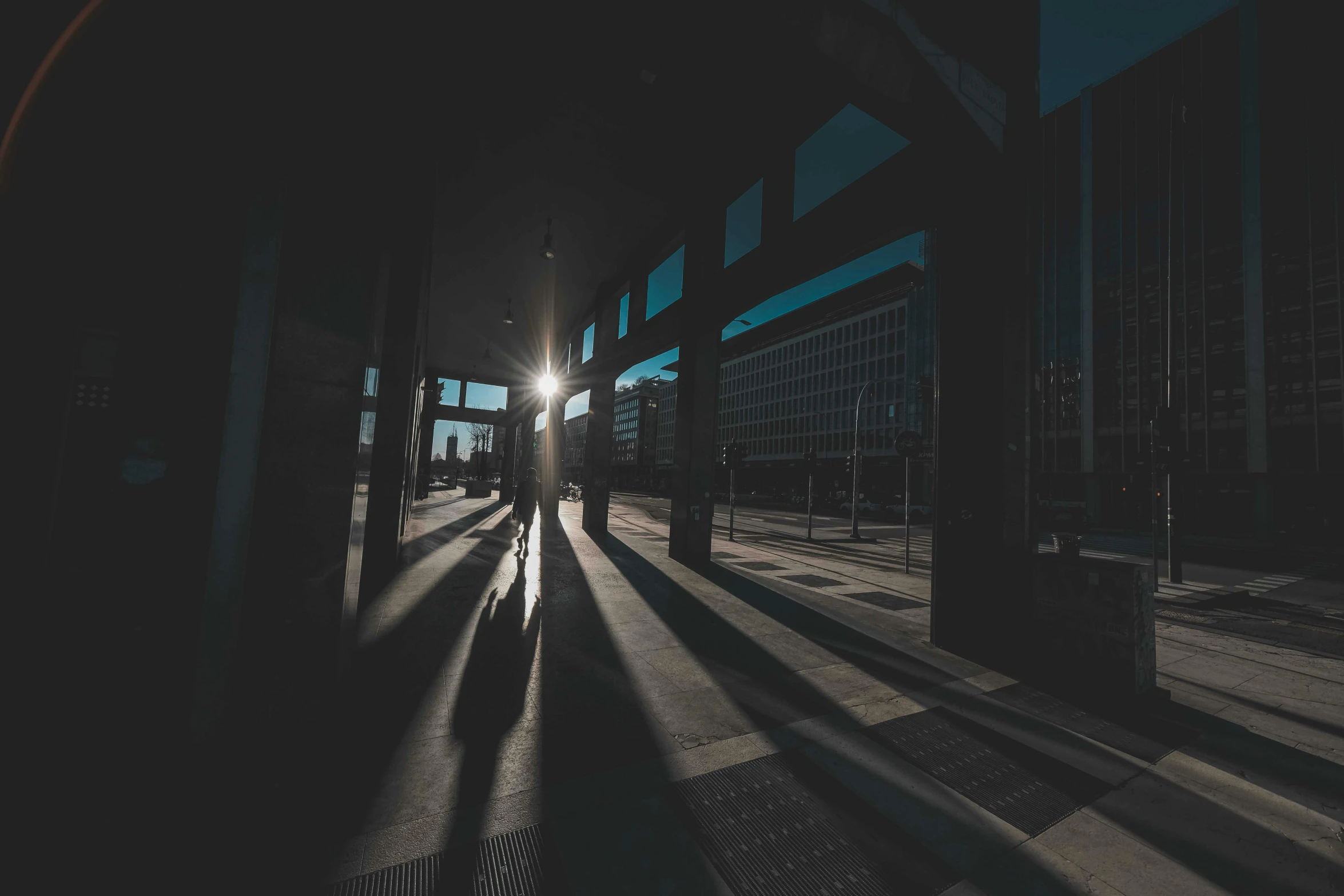 the sun shines through the windows of a train station, a picture, by Tobias Stimmer, unsplash contest winner, scary shadow people, gopro photo, dark city bus stop, light casting onto the ground