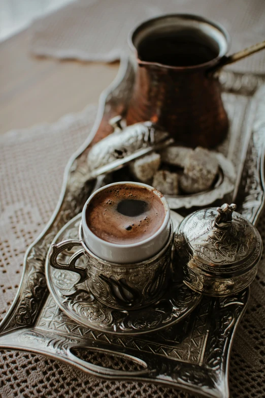 a tray that has a cup of coffee on it, a still life, by Riad Beyrouti, pexels contest winner, arabesque, made of bronze, turkey, brown, shiny and sparkling