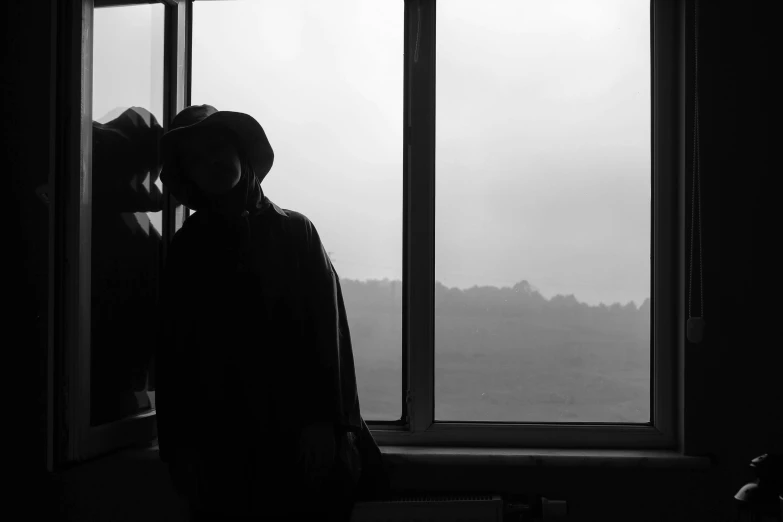 a man and a woman standing in front of a window, a black and white photo, unsplash, romanticism, woman with hat, lonely landscape, :: morning, eerie person silhouette