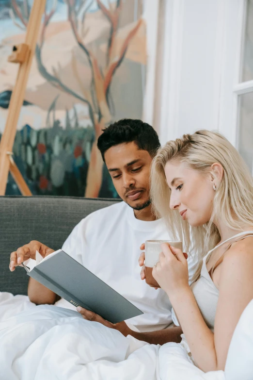 a man and woman sitting on a bed reading a book, a cartoon, pexels contest winner, millennial vibes, profile image, blonde, sleek