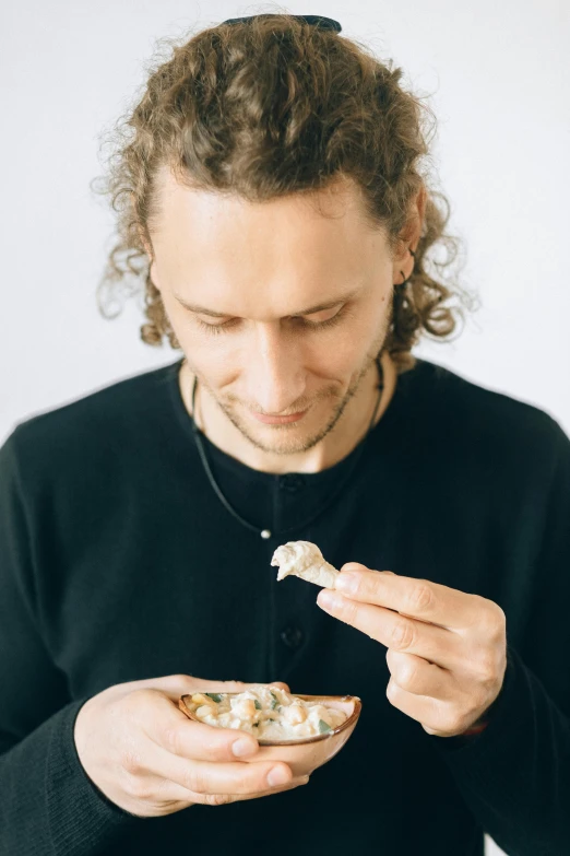 a man eating a bowl of food with a spoon, a character portrait, inspired by Quirijn van Brekelenkam, unsplash, abalone, robert sheehan, plating, on a pale background