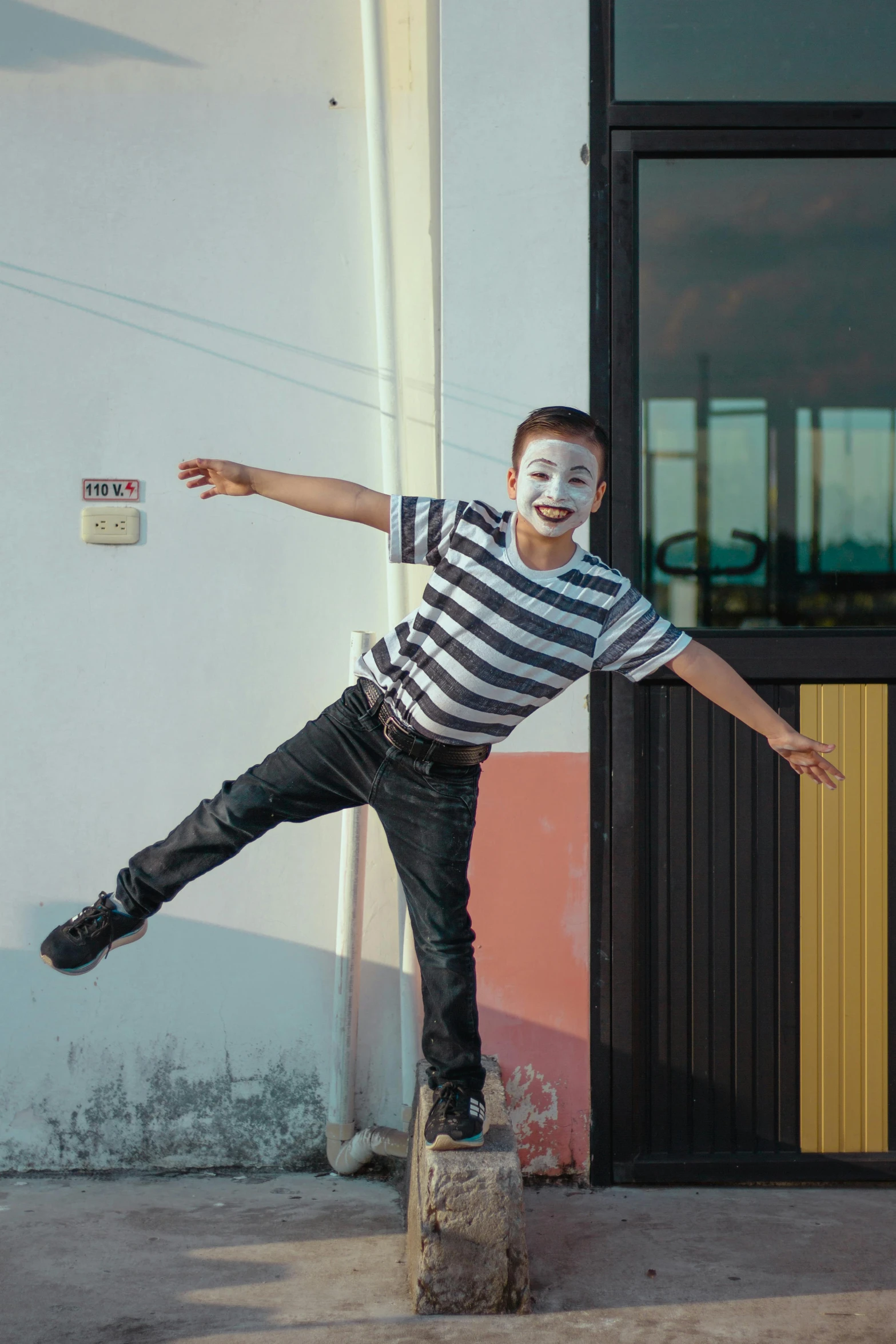 a boy in a striped shirt doing a trick on a skateboard, an album cover, pexels contest winner, happening, mime, smiling mask, portrait mode photo, dancing on a pole