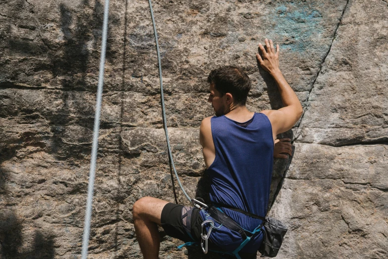 a man climbing up the side of a rock, pexels contest winner, figuration libre, wearing a tank top and shorts, belaying, profile image, back facing