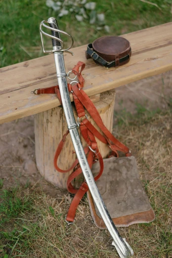 a sword sitting on top of a wooden bench, collar and leash, photograph, camp, white