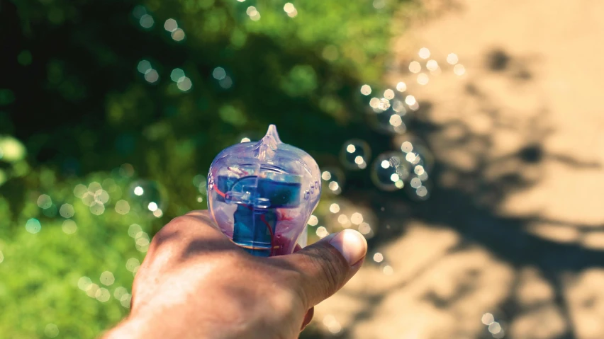 a person holding a water bottle in their hand, by Niko Henrichon, unsplash, process art, blowing bubblegum, lush garden spaceship, blue translucent resin, clutch yo - yo