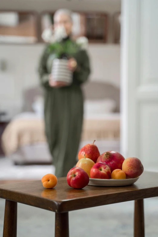 a wooden table topped with apples and oranges, inspired by Pieter de Hooch, pexels contest winner, renaissance, wearing a grey robe, hotel room, moroccan, focus on full - body