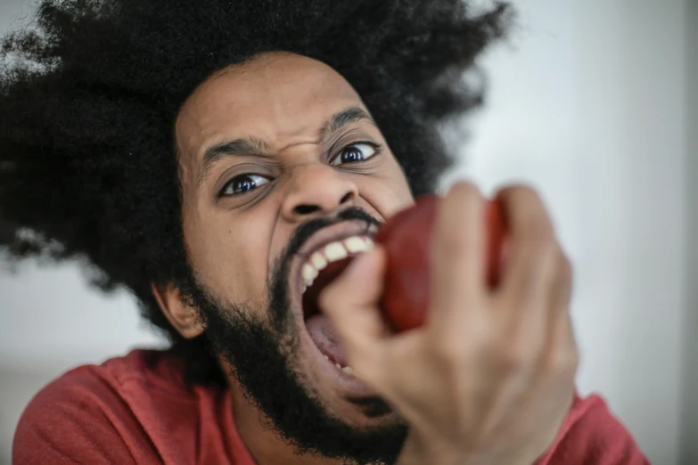 a close up of a person eating an apple, by Adam Marczyński, pexels contest winner, ray lewis yelling, afro, square, hyper anger