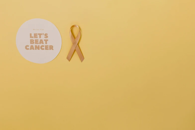 a pink ribbon next to a sticker that says let's beat cancer, by Nina Hamnett, pexels contest winner, conceptual art, yellow walls, beige color scheme, ad image, shot on sony a 7