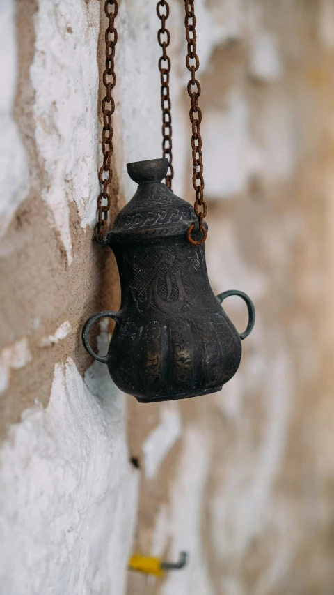 a bell hanging from a chain on a wall, inspired by Osman Hamdi Bey, unsplash, hurufiyya, hyperdetailed scp artifact jar, made of wrought iron, detailed product photo, worn