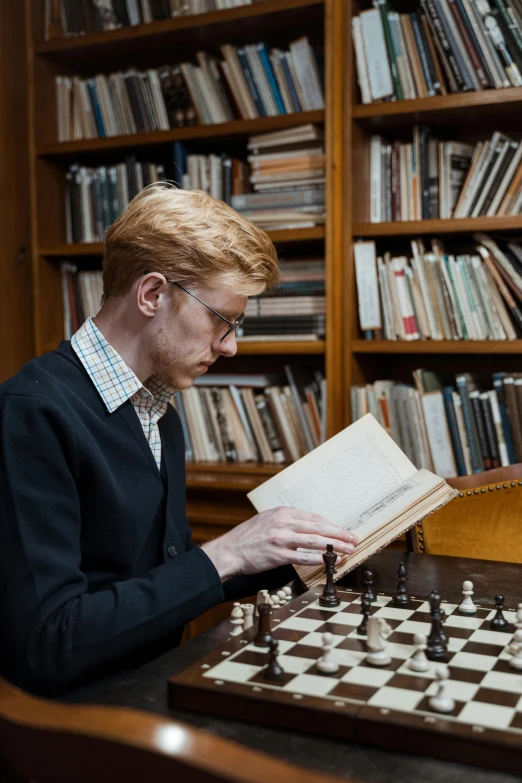 a man sitting at a table playing a game of chess, an album cover, inspired by Simon Marmion, academic art, reading in library, portrait tilda swinton, slide show, profile picture