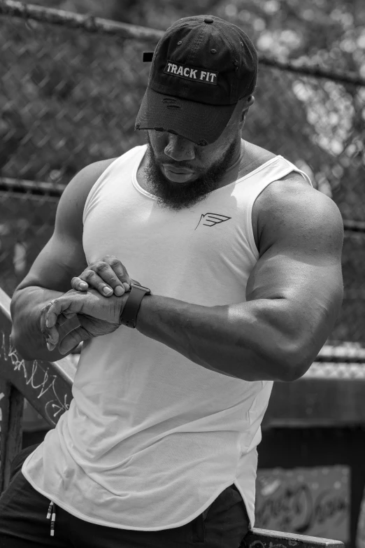 a man standing on top of a tennis court holding a racquet, a black and white photo, by Robbie Trevino, tight fitted tank top, wears a watch, profile image, bodybuilder