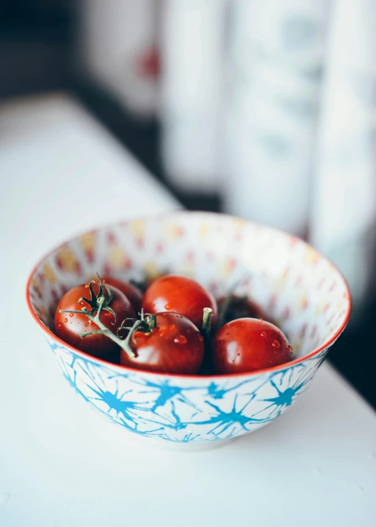 a bowl of tomatoes sitting on top of a counter, by Jessie Algie, unsplash, delicate patterned, dipped in polished blue ceramic, cheery, crisp details