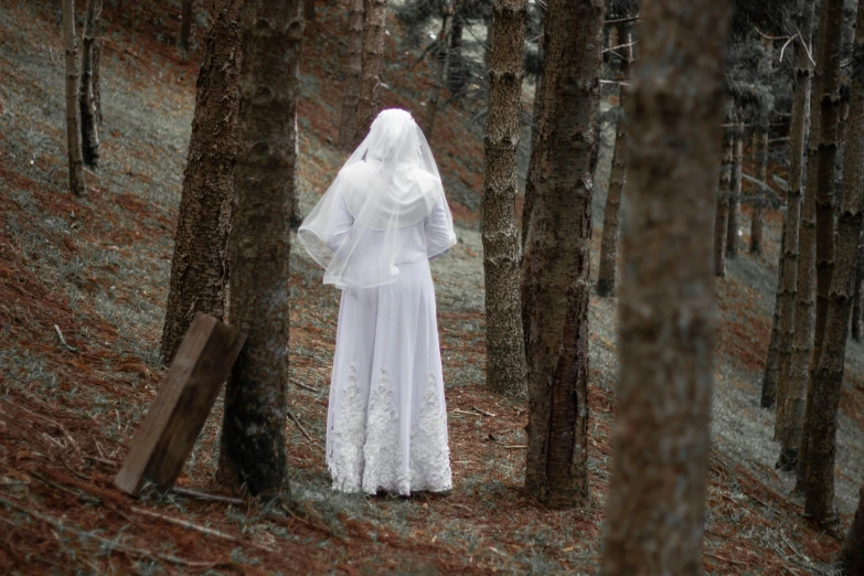 a woman in a white wedding dress standing in the woods, by Marina Abramović, unsplash, serial art, spooky found footage, nun outfit, photographed for reuters, scaring