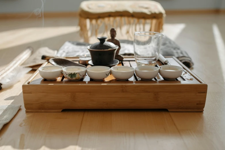 a wooden tray sitting on top of a wooden table, inspired by Kanō Shōsenin, trending on unsplash, moroccan tea set, group of seven, low-angle shot, bamboo