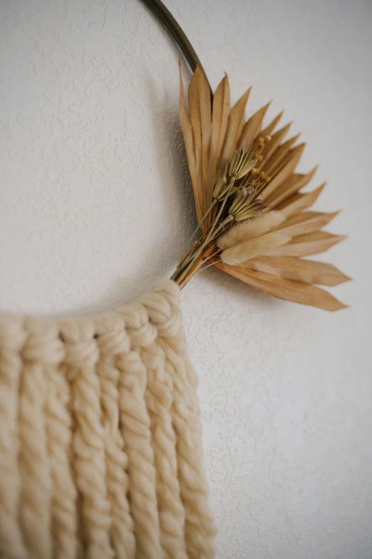 a close up of a knitted bag with a flower on it, trending on pexels, conceptual art, light - brown wall, dried palmtrees, lion's mane, wall