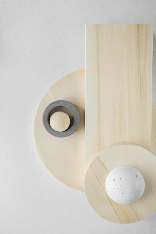 a white egg sitting on top of a wooden board, an abstract sculpture, inspired by Isamu Noguchi, trending on unsplash, kinetic art, grey colours, sconces, detail shot, knolling