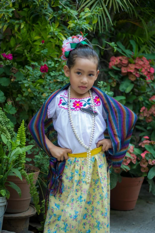 a little girl standing in front of a potted plant, inspired by Pacita Abad, flickr, quito school, wearing an elegant tribal outfit, square, wearing festive clothing, wrapped in cables and flowers