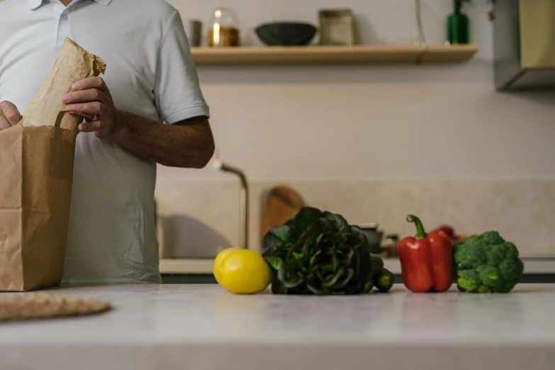 a man standing in a kitchen holding a paper bag, pexels contest winner, renaissance, vegetables on table and candle, profile image, background image, high resolution photo