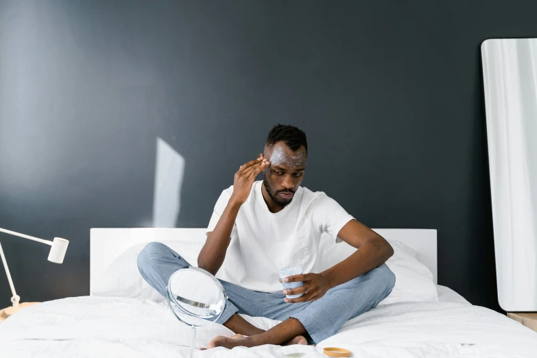 a man sitting on a bed talking on a cell phone, by Adam Marczyński, trending on pexels, happening, brown skin man egyptian prince, eye patch over left eye, skincare, chris evans hatches from an egg