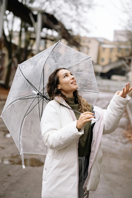 a woman in a white coat holding an umbrella, pexels contest winner, grey, gif, looking upward, rain sensor