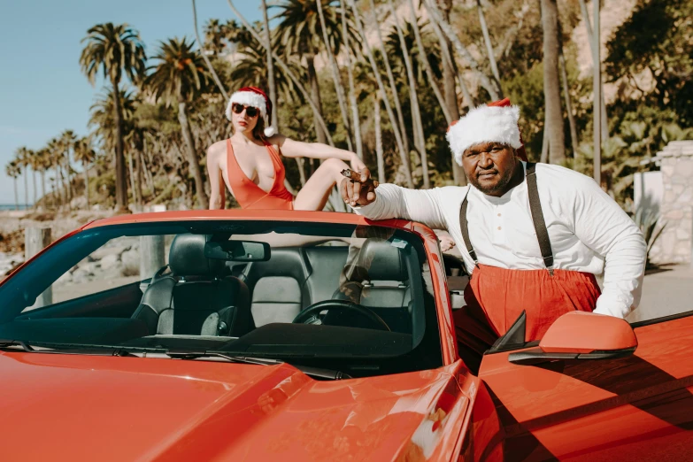 a man in a santa hat standing next to a woman in a red car, an album cover, pexels contest winner, huell babineaux, palm springs, charli bowater and artgeem, ice cube