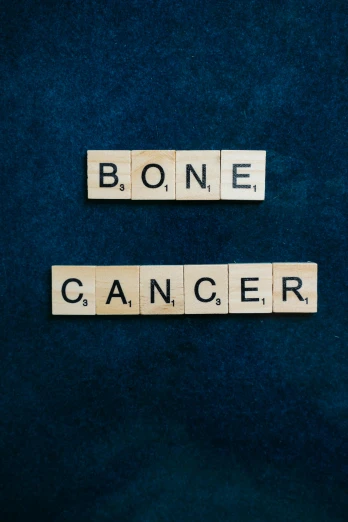 the word bone cancer spelled in scrabbles on a blue background, by Muirhead Bone, on a gray background, 15081959 21121991 01012000 4k, thumbnail, on wood