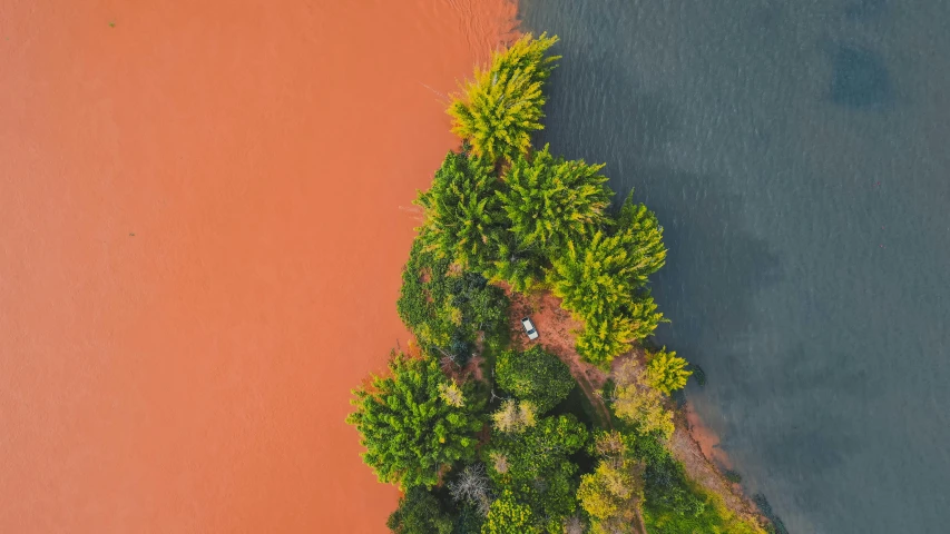 an aerial view of a body of water surrounded by trees, by Ibrahim Kodra, unsplash contest winner, red dusty soil, two colors, tourist photo, with red haze