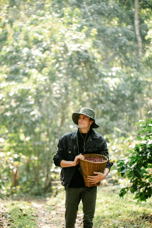 a man holding a basket of coffee beans, a portrait, by Nicolette Macnamara, sumatraism, standing in the forrest, joe keery, press shot, caracter with brown hat