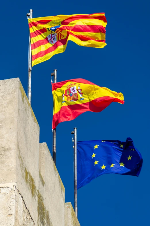 a couple of flags that are flying in the air, a portrait, inspired by Juan Giménez, unsplash, the three moiras, in spain, square, high quality photo