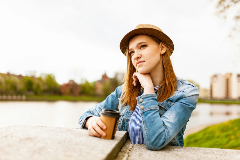 a woman leaning on a wall with a cup of coffee, happening, brown hat, sitting on a park bench, avatar image, cute young redhead girl