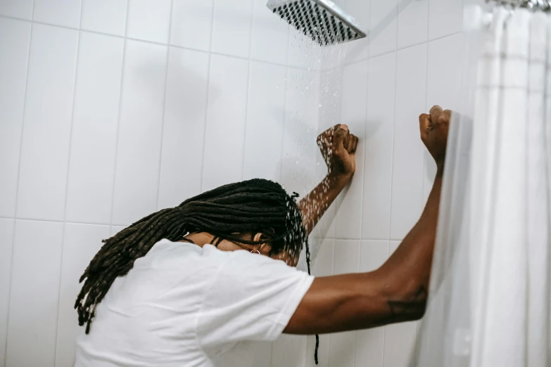 a man with dreadlocks washing his face in a shower, by Julia Pishtar, pexels contest winner, clean minimalist design, long afro hair, facing away from camera, waking up