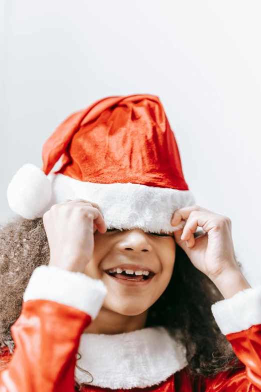 a little girl wearing a santa hat covering her eyes, incoherents, zoomed in, avatar image, product shot, small wide smile