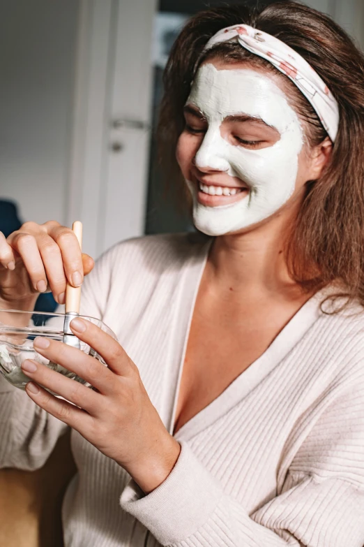 a woman putting a facial mask on her face, trending on pexels, renaissance, a still of a happy, college, face and body, wearing a grey robe
