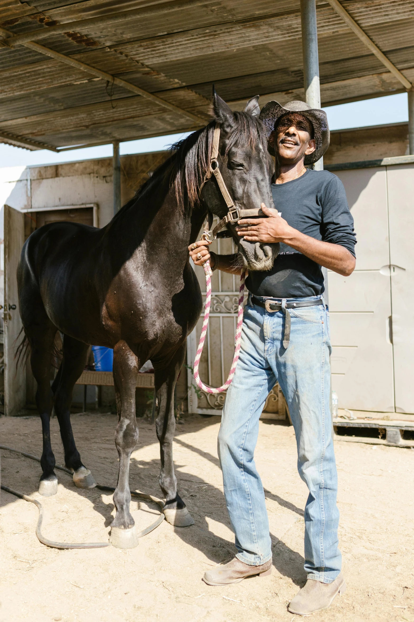 a man standing next to a horse in a barn, african ameera al taweel, with black, australian, mechanic